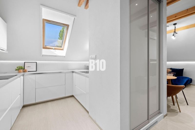 Helle Küchenzeile mit Fenster und Holzboden in einer 2-Zimmer-Wohnung.