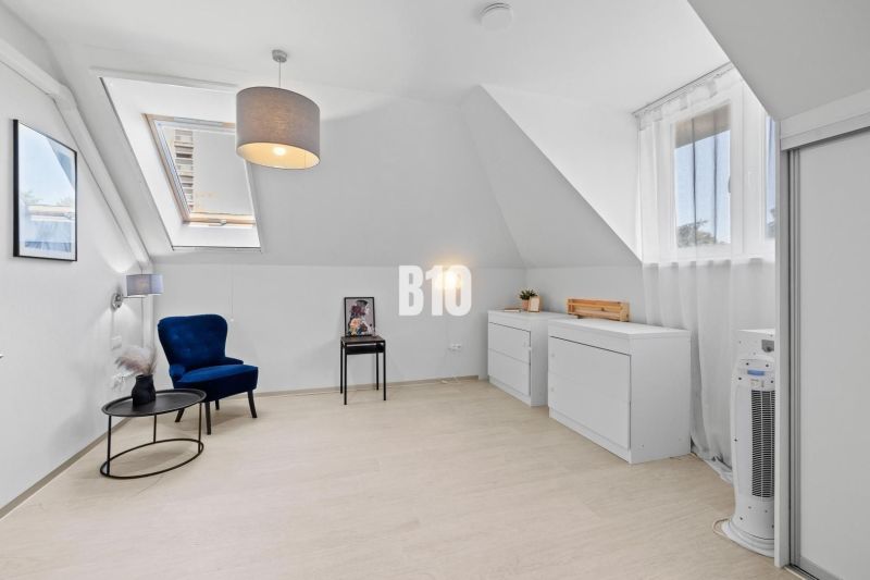 Ein heller Raum mit Holzelementen, einem blauen Sessel und zwei Kommoden in einer Zweizimmerwohnung.
