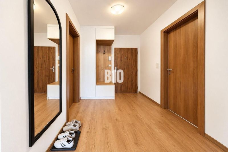 Heller Flur mit Holzdekorboden und großem Spiegel in einer 2-Zimmer-Wohnung.