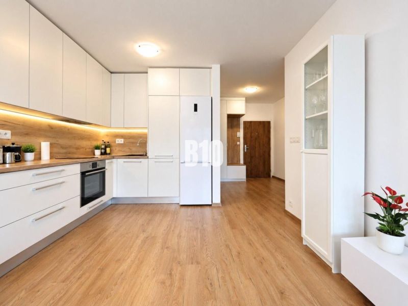 Küche in einer 2-Zimmer-Wohnung mit weißer Küchenzeile und Boden in Holzoptik.