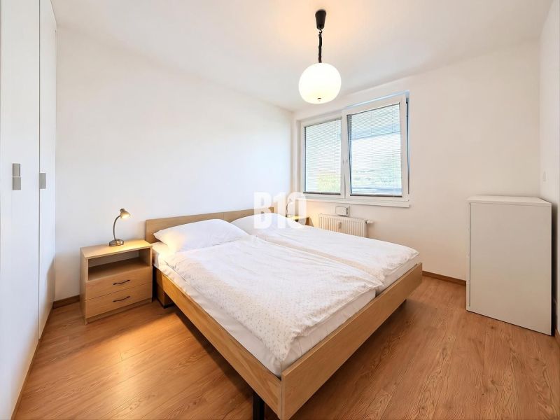 Schlafzimmer in einer 2-Zimmer-Wohnung mit Bett, Nachttisch und Holzboden.