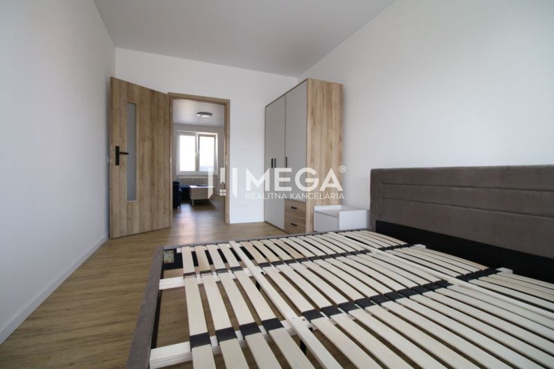 Schlafzimmer in einer 2-Zimmer-Wohnung mit Holzboden und einfacher Einrichtung.