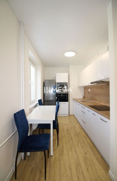 Küche mit weißen Schränken und Holzboden in einer Zweizimmerwohnung.