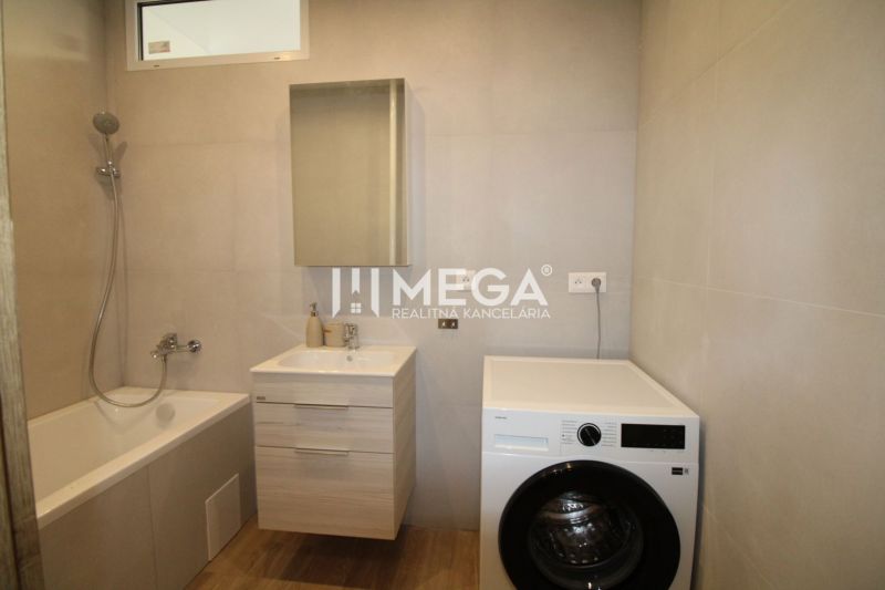 Badezimmer in einer 2-Zimmer-Wohnung mit Badewanne, Waschmaschine und Boden mit Holzdekor.