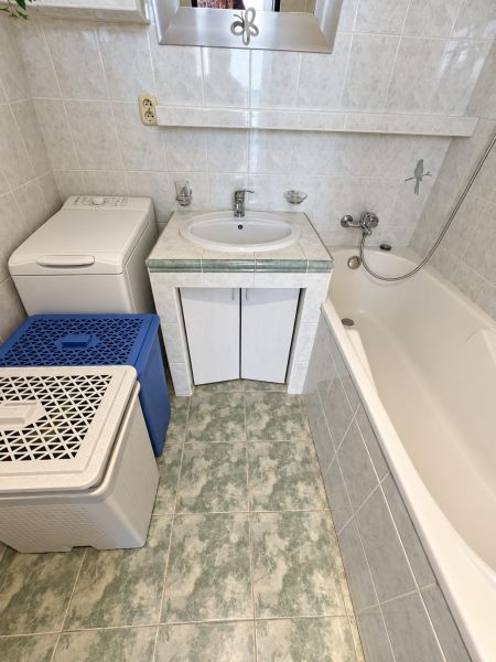 Badezimmer mit Waschbecken, Badewanne und Waschmaschine in einer 3-Zimmer-Wohnung, Fliesen in hellem Farbton.