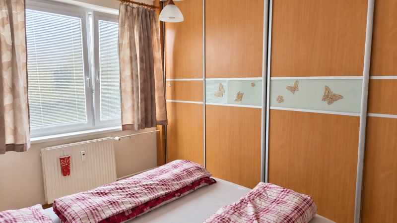 Schlafzimmer in einer 3-Zimmer-Wohnung mit Einbauschrank und Bett mit roter Bettwäsche.