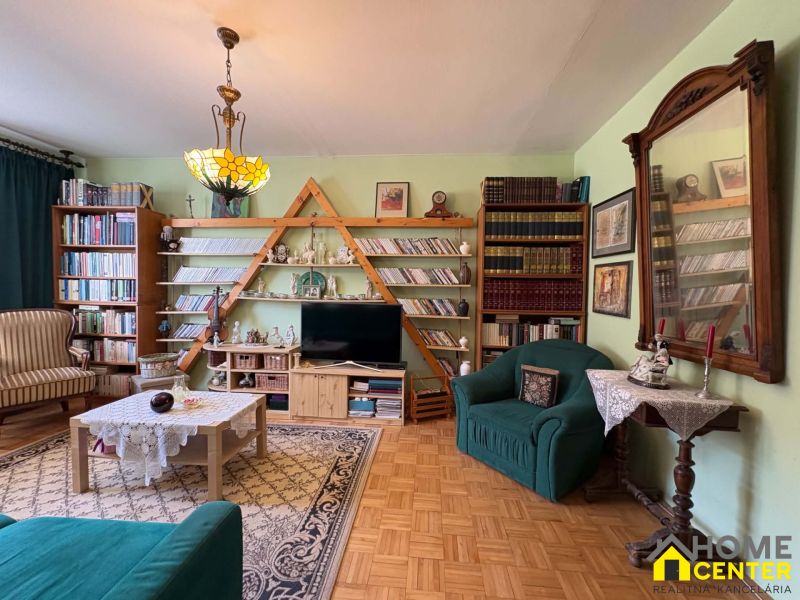 Wohnzimmer in einer 3-Zimmer-Wohnung mit Holzboden und einer umfangreichen Bibliothek.