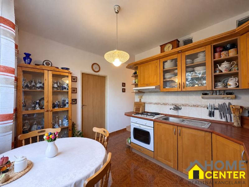 Küche in einer 3-Zimmer-Wohnung mit Holzelementen, Tellern und einer Vase mit Blumen.