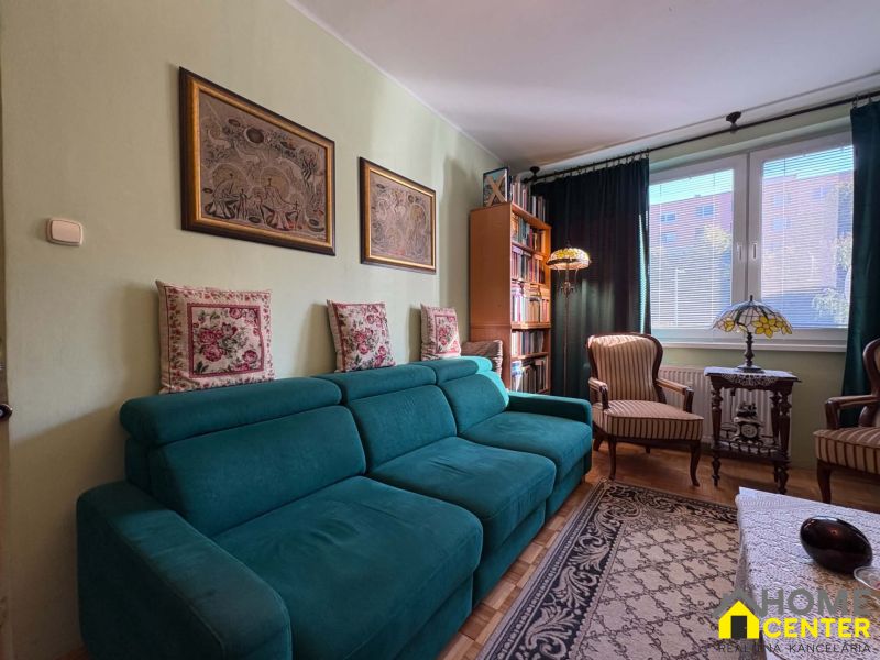 Wohnzimmer in einer 3-Zimmer-Wohnung mit einer türkisfarbenen Couch und dekorativen Kissen.