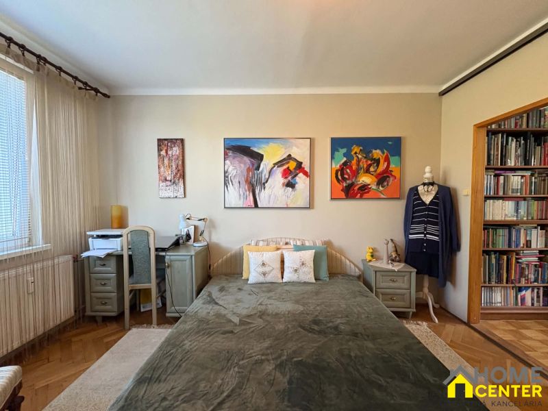 Schlafzimmer in einer 3-Zimmer-Wohnung mit Holzboden und Kunstgemälden an der Wand.