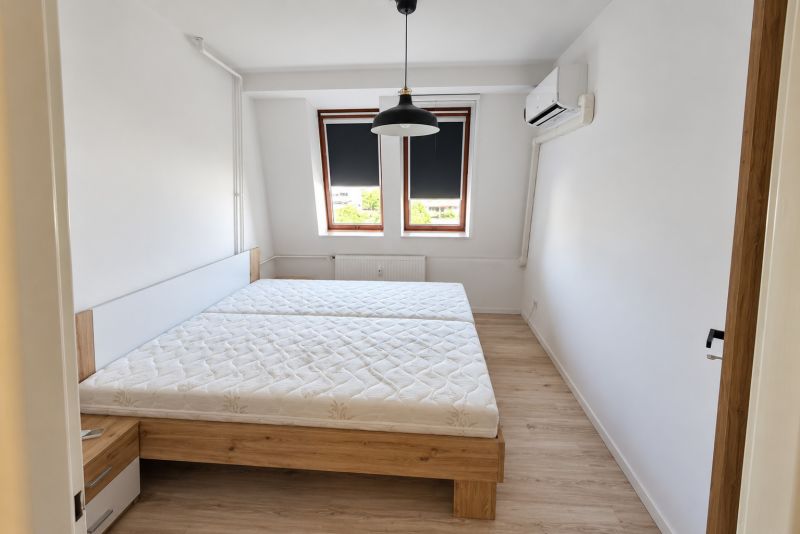 Schlafzimmer mit Bett, Klimaanlage und Holzboden in einer 2-Zimmer-Wohnung.