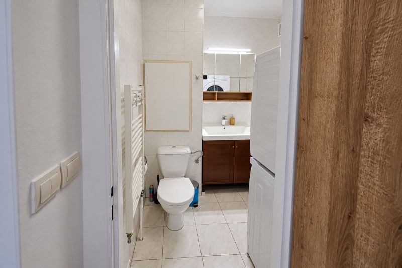 Badezimmer mit Waschbecken, Toilette und Waschmaschine in einer 2-Zimmer-Wohnung.