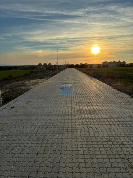Ein befestigter Weg in den Weinbergen in Senica bei Dämmerung mit Blick auf die Stadt.