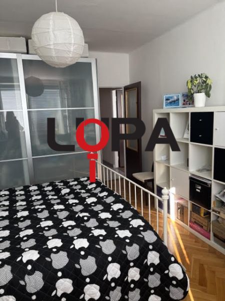 Schlafzimmer in einer 2-Zimmer-Wohnung mit Stauraum, Bett und Bodenbelag in Holzoptik.