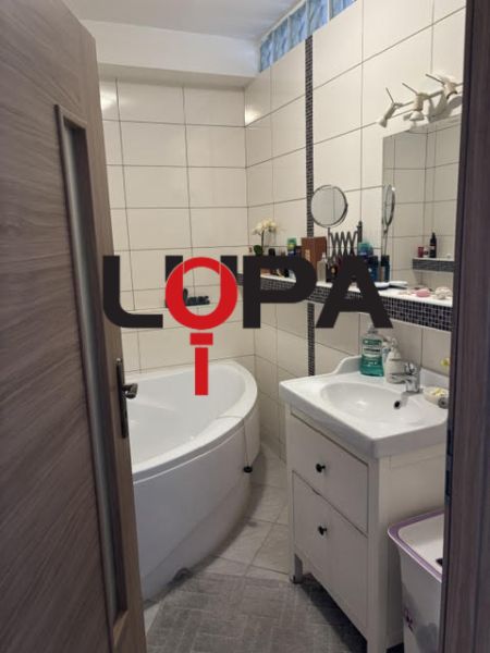 Badezimmer in einer 2-Zimmer-Wohnung mit Badewanne, Waschbecken und weißen Fliesen.