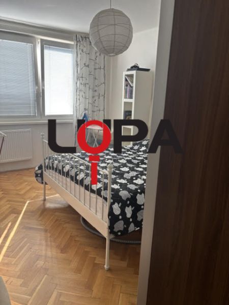 Schlafzimmer in einer 2-Zimmer-Wohnung mit einem Bett und einem Boden in Holzoptik.