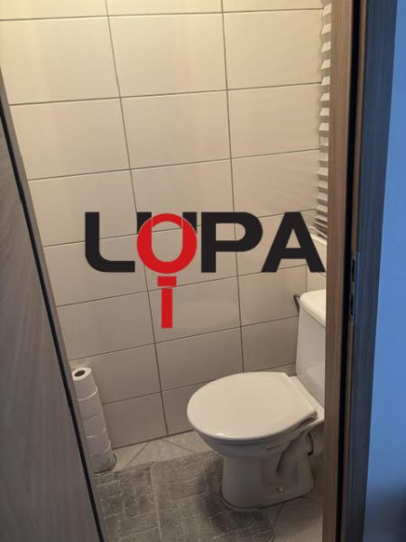 Toilette mit einfacher Verkleidung und Fliesen in einer 2-Zimmer-Wohnung.