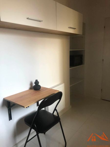 Arbeitsbereich in einer 2-Zimmer-Wohnung mit ausklappbarem Tisch und Regal.
