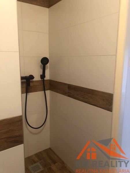 Duschkabine mit Keramikfliesen und Duschkopf in einer 2-Zimmer-Wohnung.