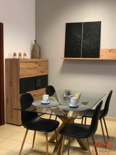 Glastisch mit vier Stühlen, Dekorationen und Regal in einer 2-Zimmer-Wohnung.