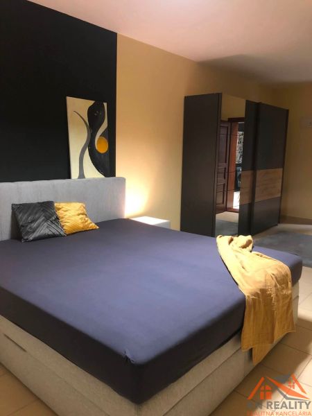 Schlafzimmer mit Doppelbett, Kleiderschrank und abstrakter Kunst in einer 2-Zimmer-Wohnung.