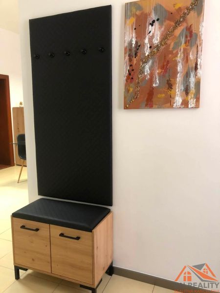 Kommode und Kleiderständer mit schwarzem Paneel im Flur einer Zweizimmerwohnung.