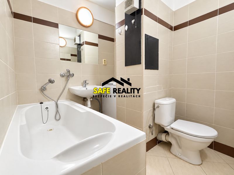 Badezimmer in einer Einzimmerwohnung mit Badewanne, Waschbecken und WC, gefliest mit hellen Fliesen.