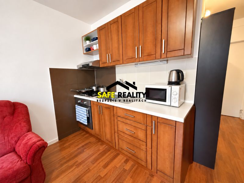 Küche in einer Einzimmerwohnung mit Holzboden und Geräten.