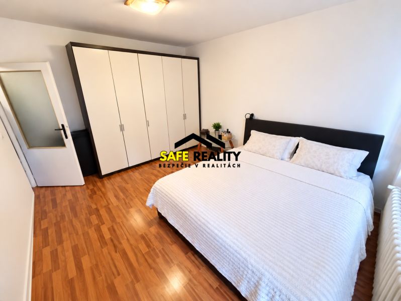 Schlafzimmer mit Holzboden und großem Schrank in einer Einzimmerwohnung.