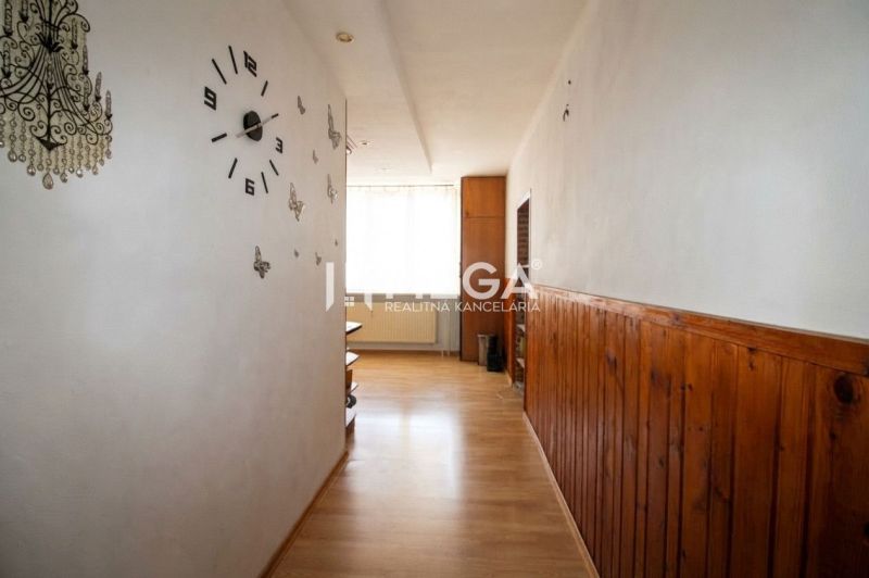 Der Flur in einer 3-Zimmer-Wohnung mit einem Boden in Holzoptik und einer Wanduhr.