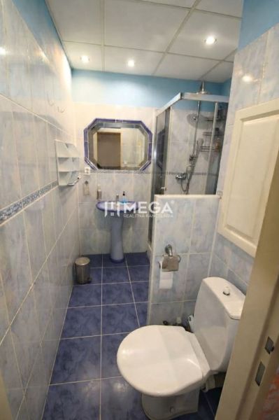 Badezimmer in einer 3-Zimmer-Wohnung mit blauen Fliesen, Dusche und Spiegel.