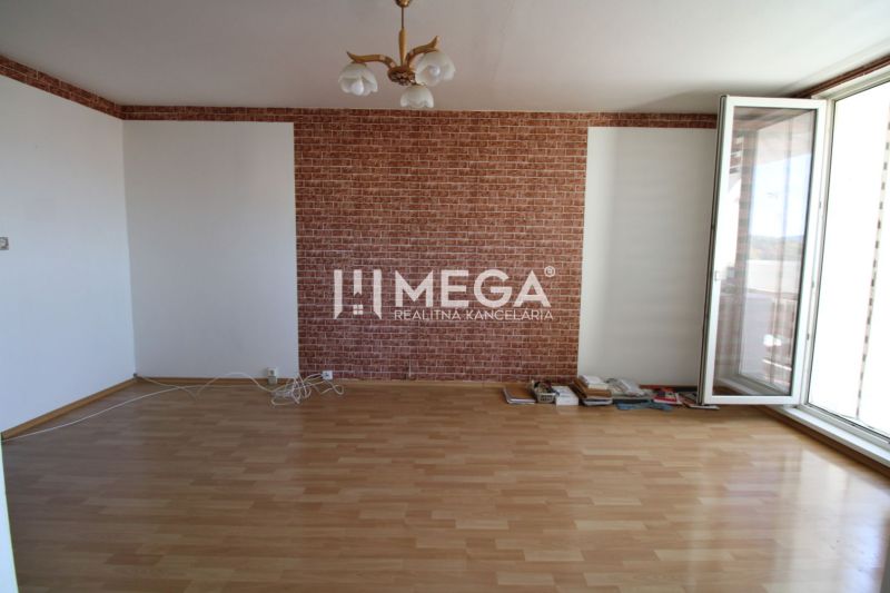 Ein Zimmer mit Ziegelverkleidung, einem Holzboden und einem großen Fenster in einer 3-Zimmer-Wohnung.