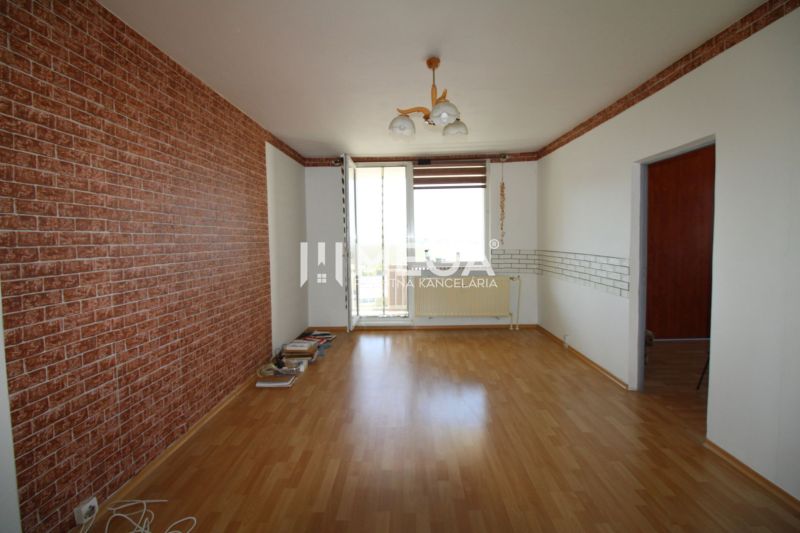 Ein Zimmer in einer 3-Zimmer-Wohnung mit einem Boden in Holzoptik und einer Tapete in Ziegeloptik.