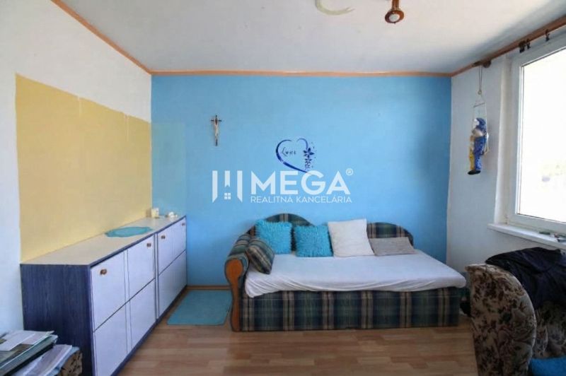 Ein Zimmer mit blauer Wand, Sofa und Schrank in einer 3-Zimmer-Wohnung mit Holzboden.