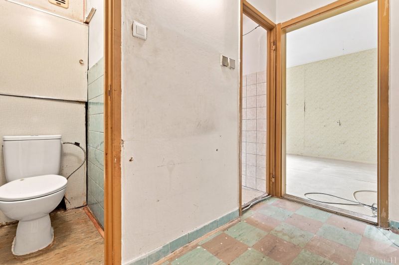 Flur einer 2-Zimmer-Wohnung mit freiliegender Wand, Toilette und Zugang zum Raum.