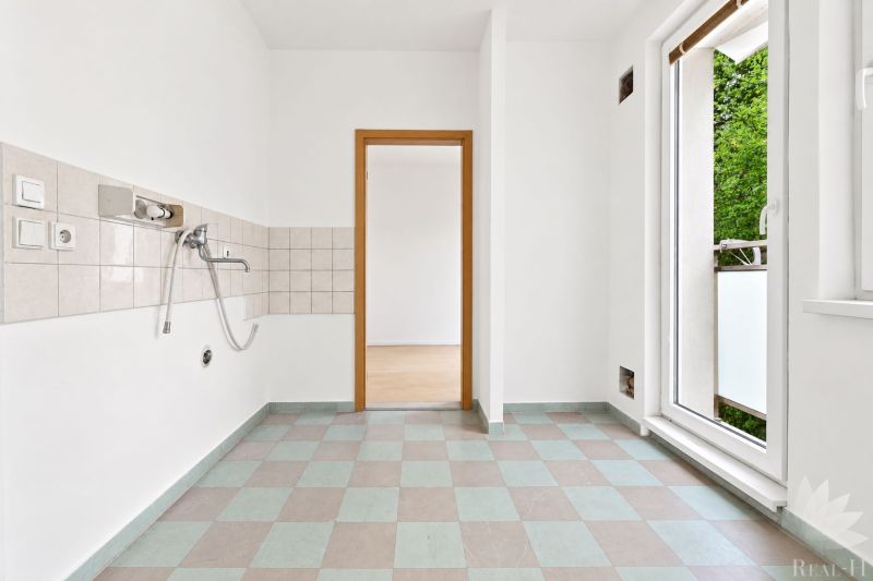 Küche in einer 2-Zimmer-Wohnung mit Fliesen und Balkontür.