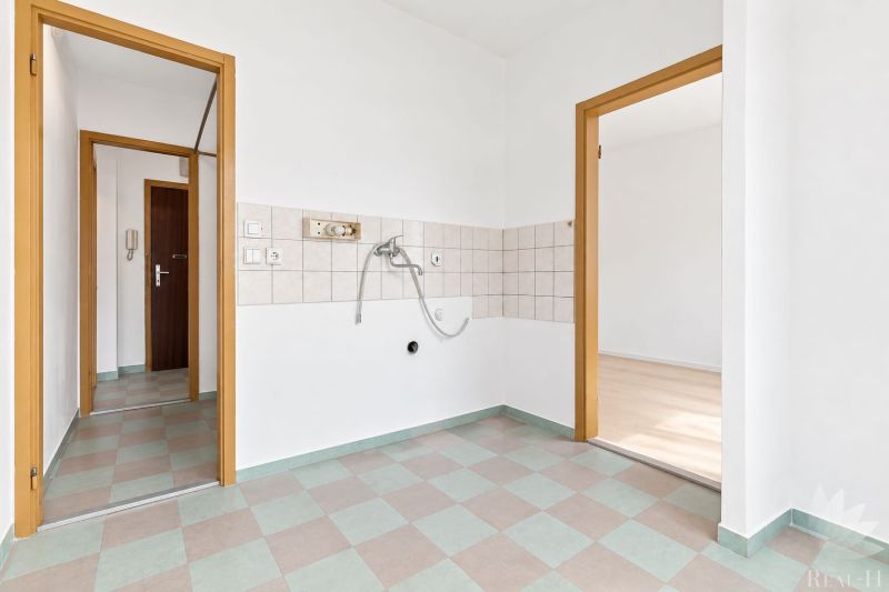 Geräumige Küche in einer 2-Zimmer-Wohnung mit Fliesen an den Wänden.