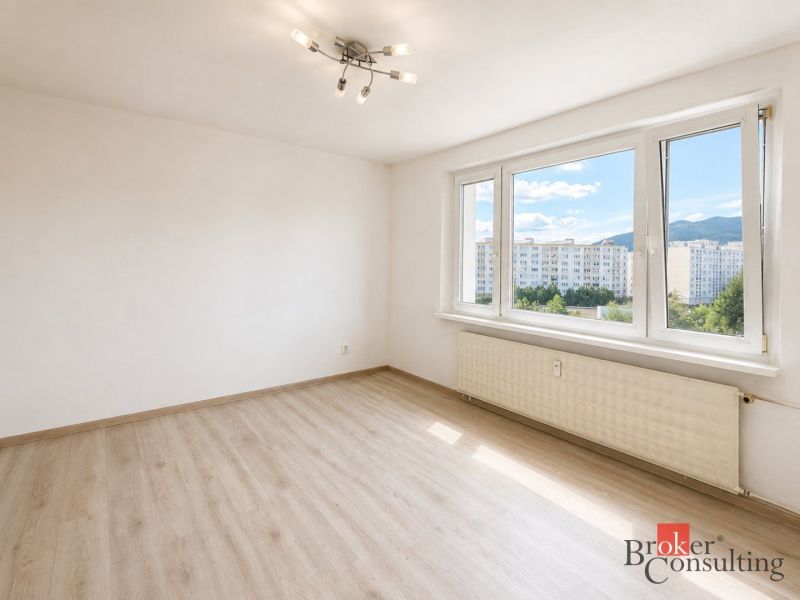 Ein Zimmer mit großen Fenstern und einem Boden in Holzoptik in einer 3-Zimmer-Wohnung.