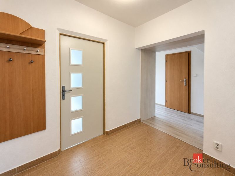 Flur einer 3-Zimmer-Wohnung mit Garderobe und Boden in Holzoptik.