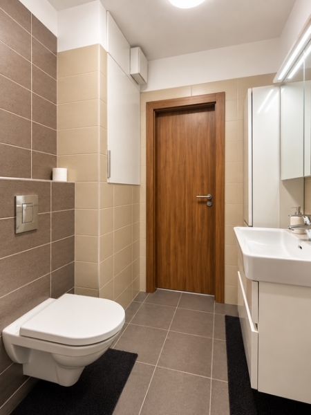 Badezimmer in einer 2-Zimmer-Wohnung mit Fliesen und hängender Toilette.