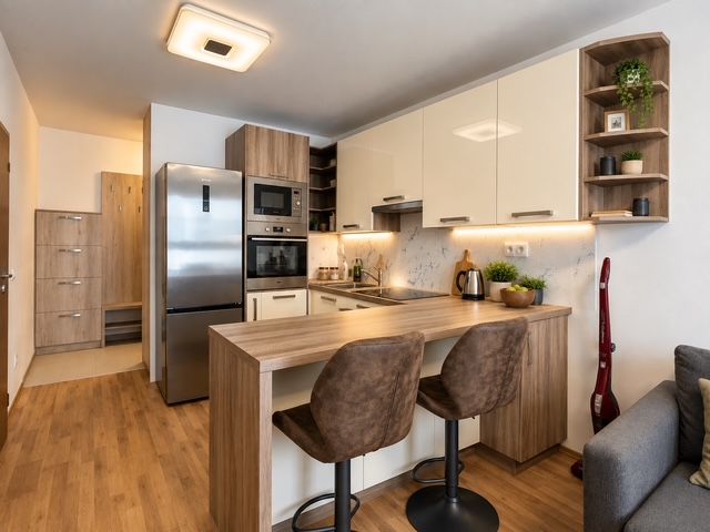 Küche in einer 2-Zimmer-Wohnung mit Geräten und Bodenbelag in Holzoptik.
