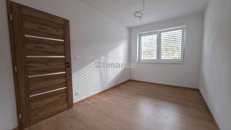 Ein Zimmer mit einem Boden in Holzoptik, weißen Wänden und einem großen Fenster, Einfamilienhaus.
