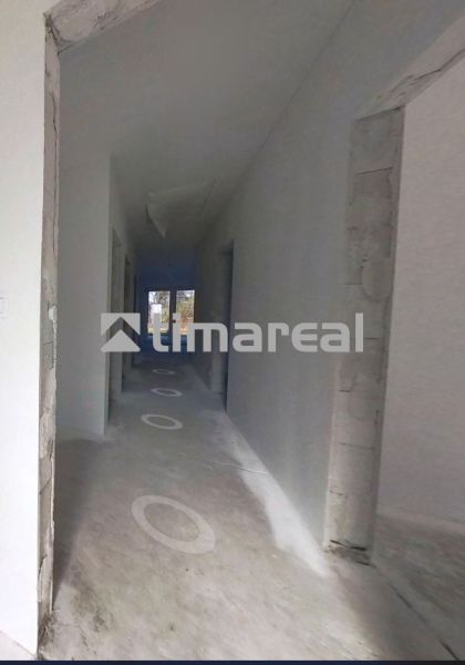 Ein Flur in einem Einfamilienhaus mit unfertigem Boden und nackten Wänden.
