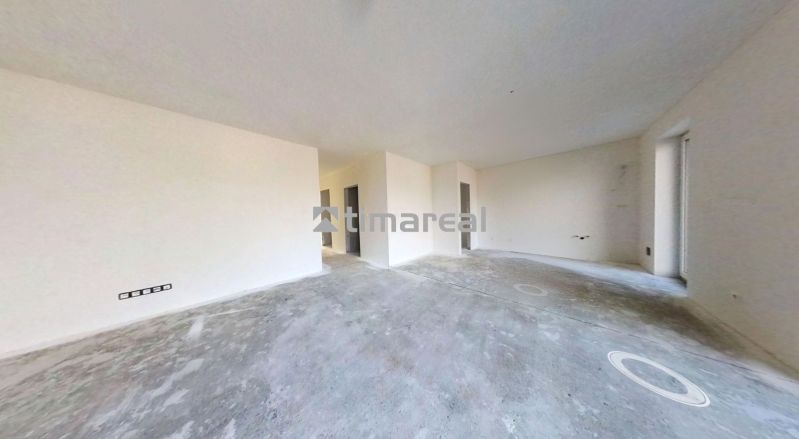 Ein leerer Raum in einem Einfamilienhaus mit Betonboden und weißen Wänden.