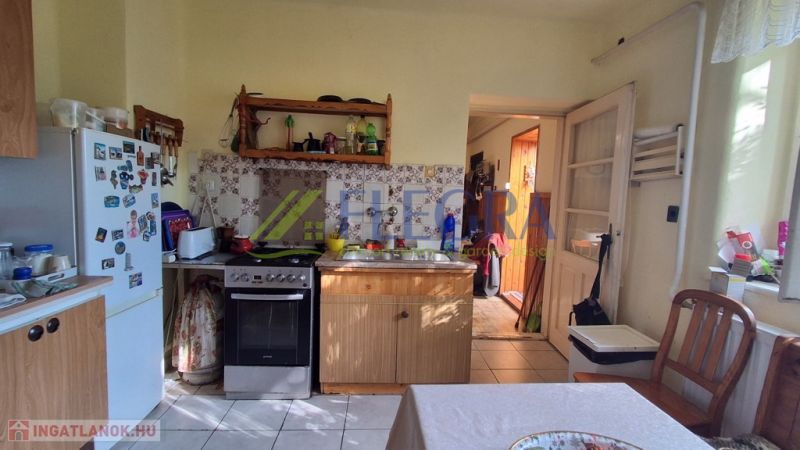 Küche in einem Einfamilienhaus mit Holzmöbeln, Kühlschrank und Elektroherd.