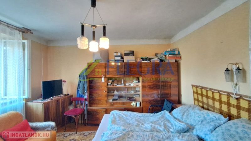 Ein Zimmer in einem Einfamilienhaus mit Möbeln, einem Bett und einem Fernseher, einfaches Interieur.
