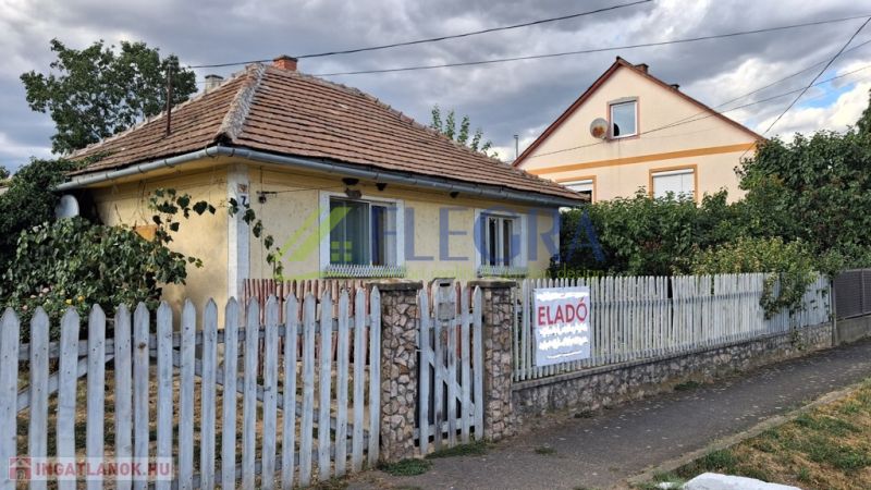 Ein Einfamilienhaus in Tornyosnémeti mit einem Ziegeldach und einem bunten Zaun.