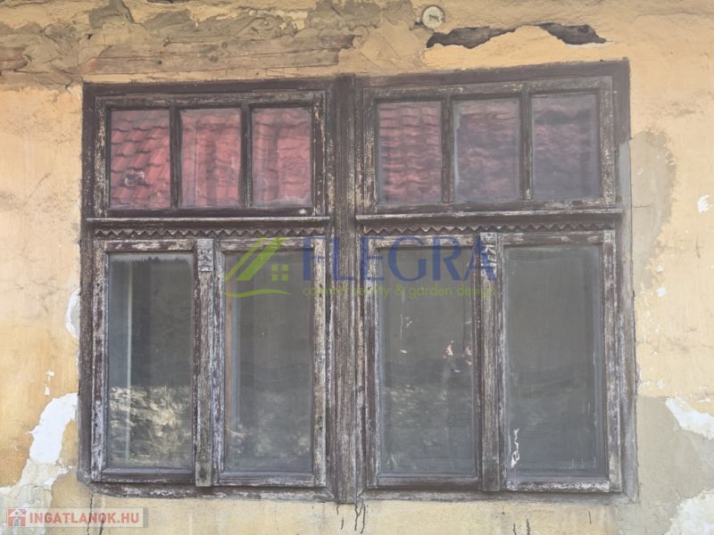 Abgebröckelter Putz und altes Holzfenster an einem Einfamilienhaus in Hejce.