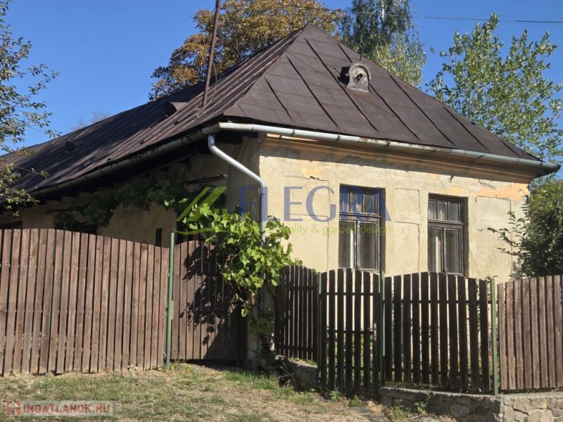 Ein älteres Einfamilienhaus in Hejce mit einem Schrägdach und einem Holzzaun.