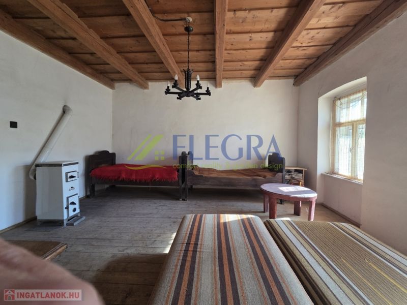 Ein Zimmer in einem Einfamilienhaus mit Holzbalkendecke und Kachelofen.